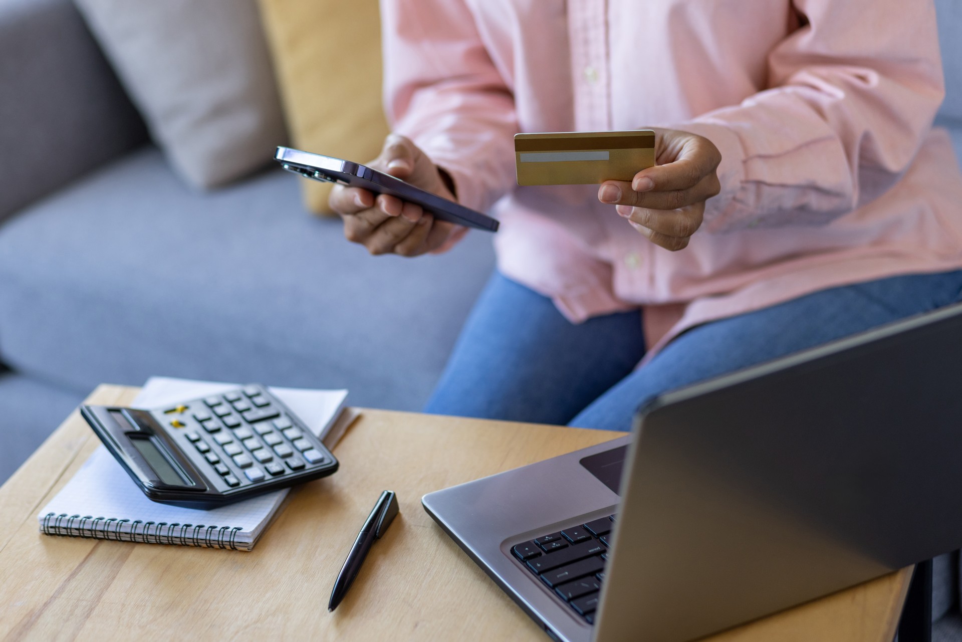 Woman making online payment with credit card and smartphone in a relaxed home setting